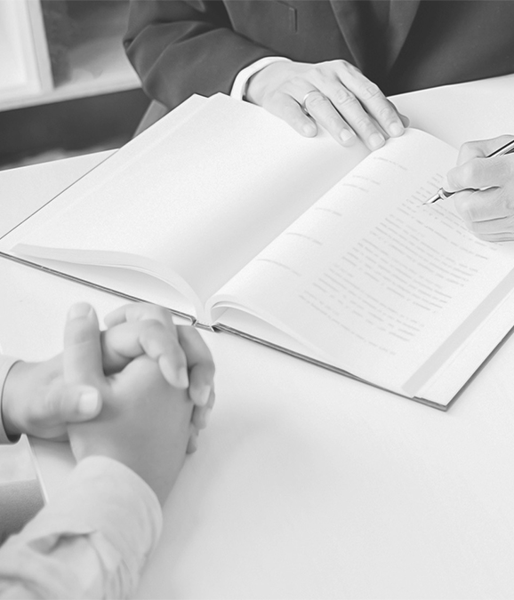 Lawyer writing notes in an open legal book while meeting with a client, legal consultation and advice.