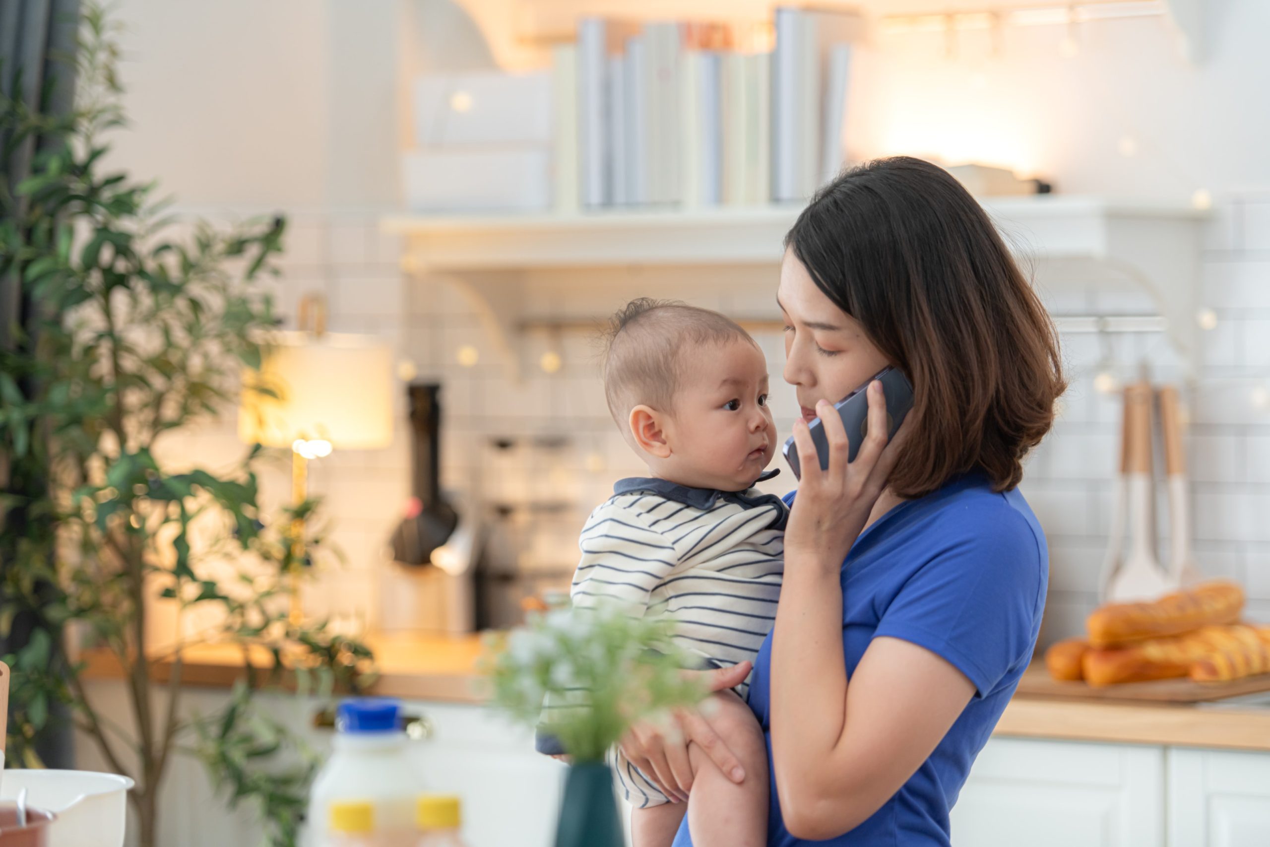 Mother and tiny child in the kitchen preparing dinner mother calling emergency