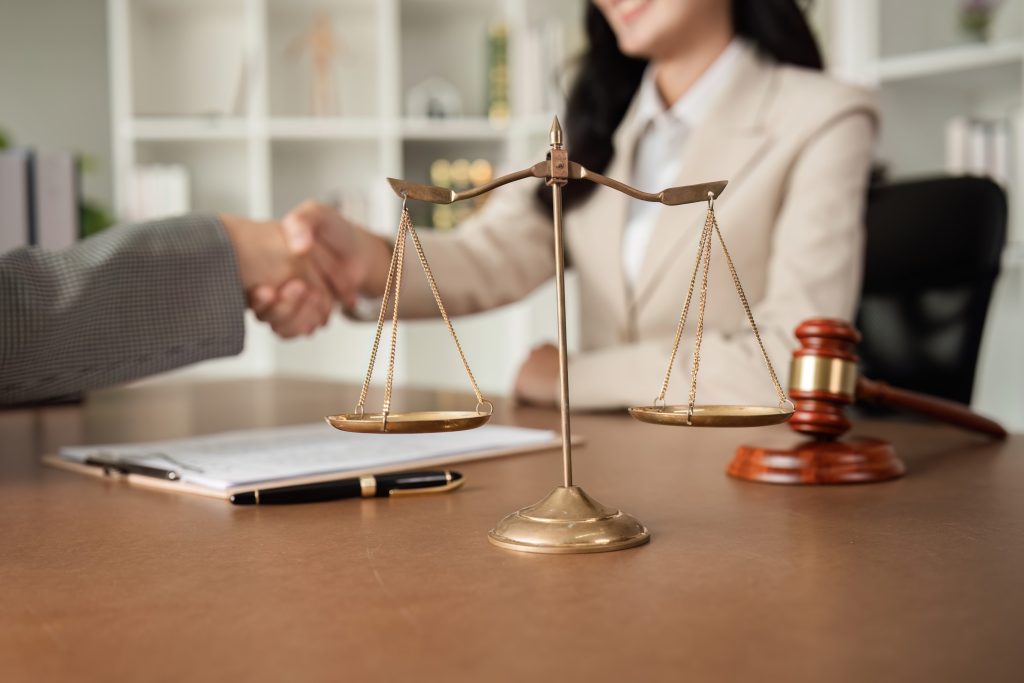 Lawyer and client handshake with scales of justice and gavel, symbolising trusted legal advice in Liverpool NSW