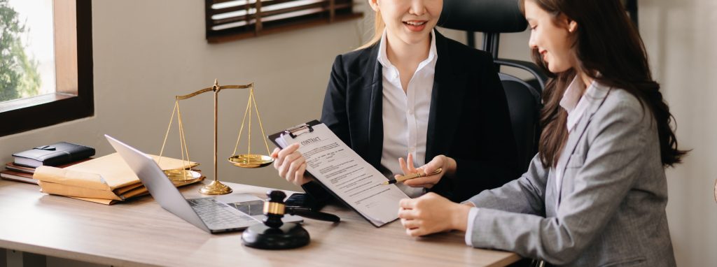 Business and lawyers discussing contract papers with brass scale on desk in office.